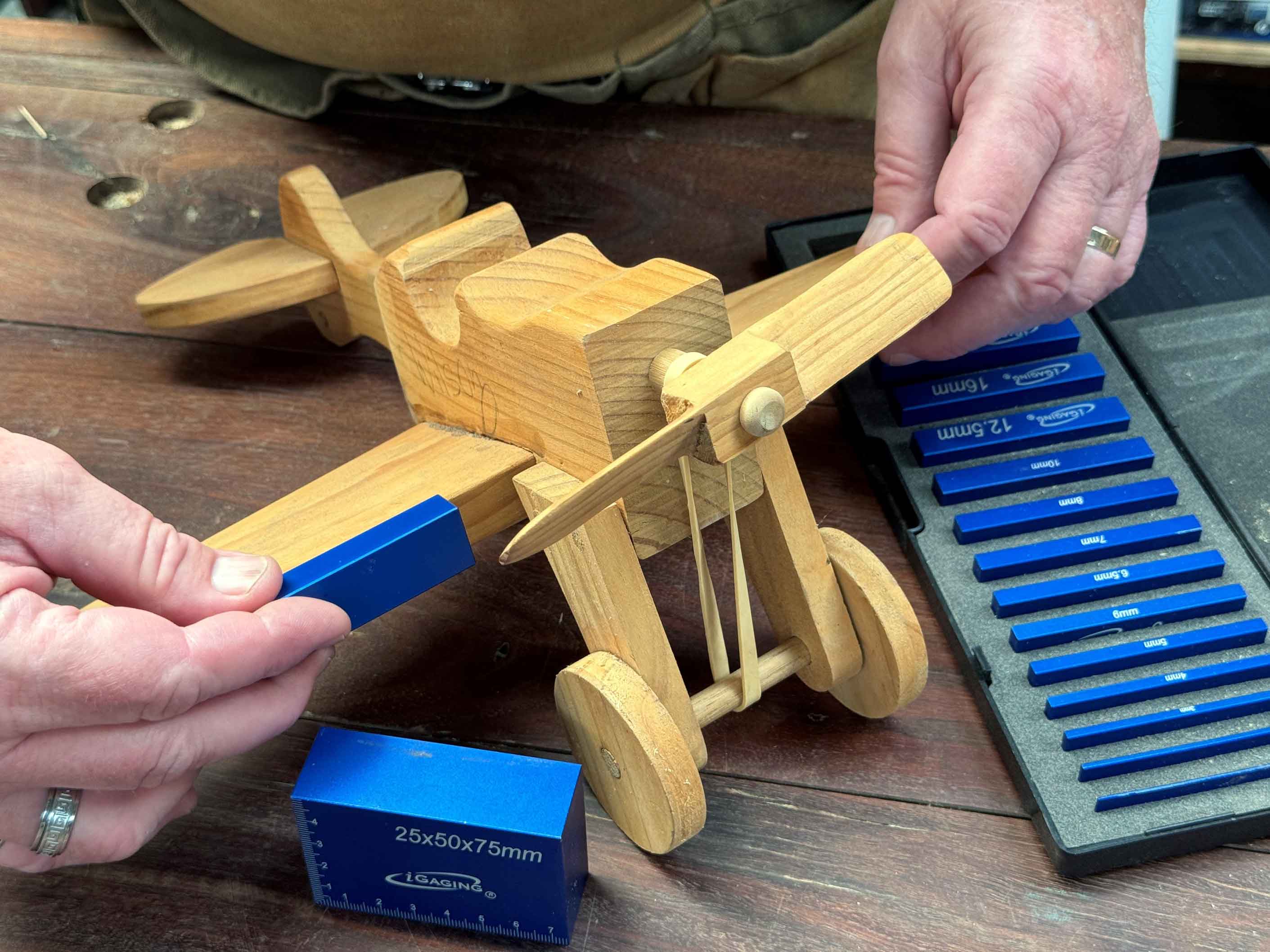 Measuring up with low vision 1 Mans hands holding a wooden airplane child’s toy while using a set of blue Right On Precision Setup Blocks