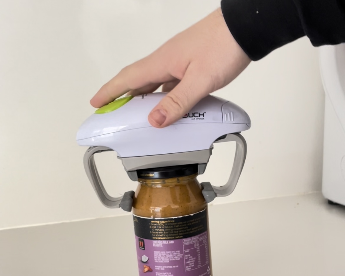 A mans hand is rested on top of the One Touch Jar Opener