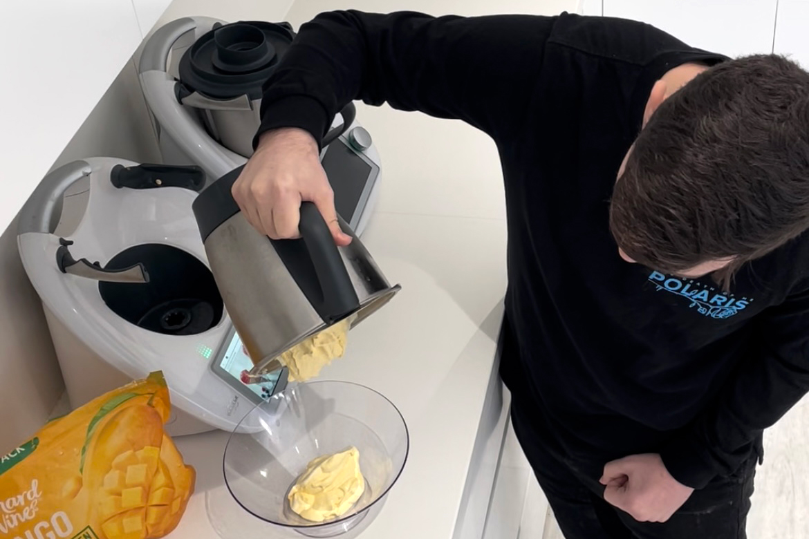 Jayden using his Thermomix web A man in his kitchen tipping a mixture from his Thermomix into a bowl.