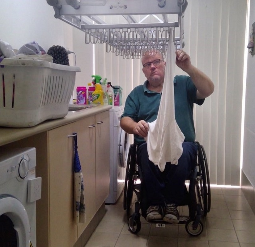 man using clothes line man using a wheelchair hangs up his laundry on mechanical clothes line