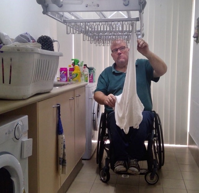 man using a wheelchair hangs up his laundry on mechanical clothes line