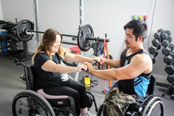 A lady and a man workout in the gym from their wheelchairs. A lady and a man workout in the gym from their wheelchairs.