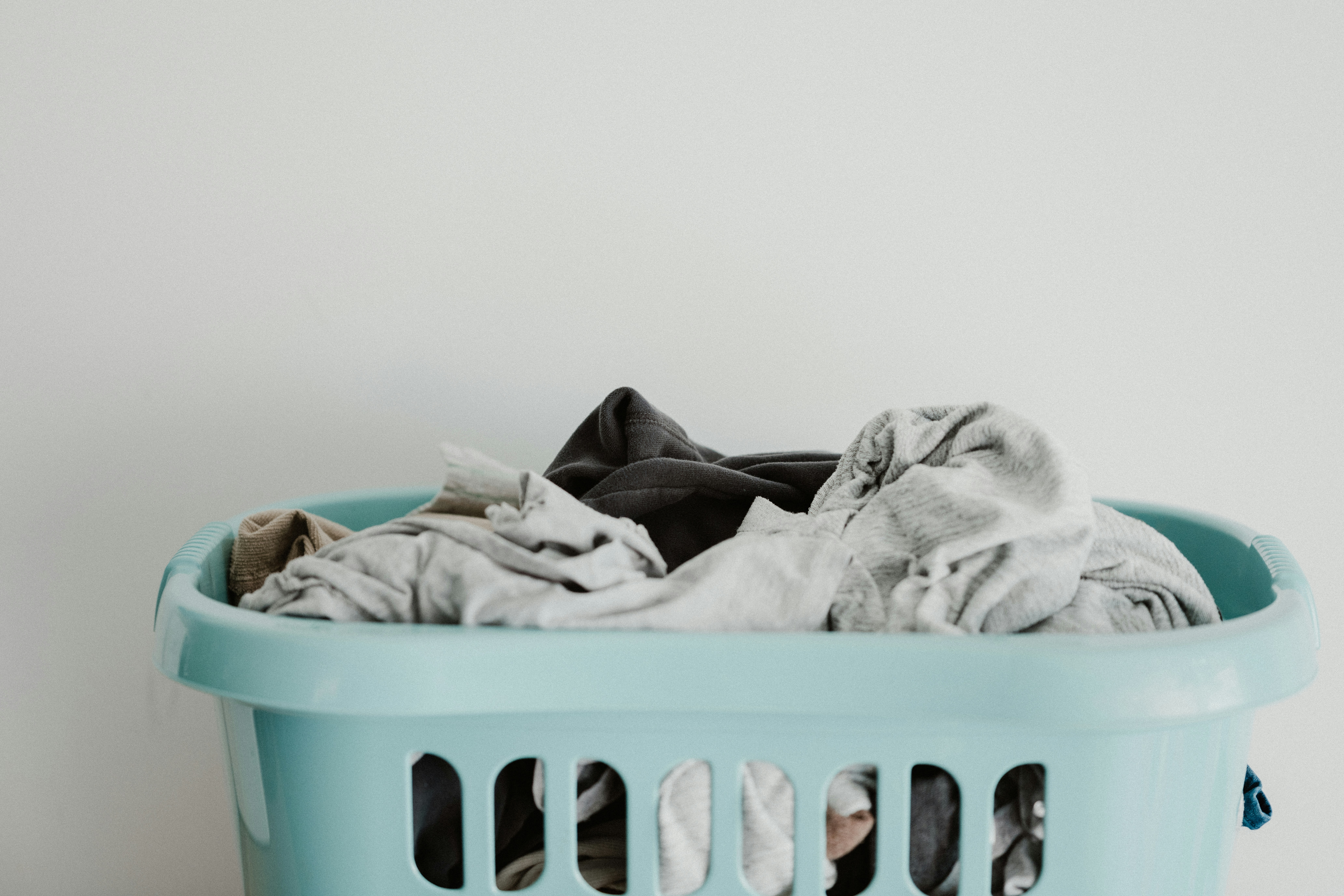 annie-spratt-5TfCI4nj6B4-unsplash a laundry basket with assorted cloth items