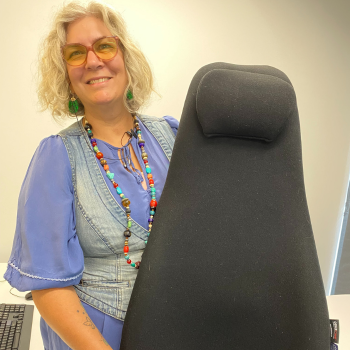A photo of a woman holding a back support cushion, while talking and smiling