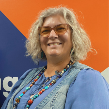 Photo of a woman smiling with glasses and a colourful necklace