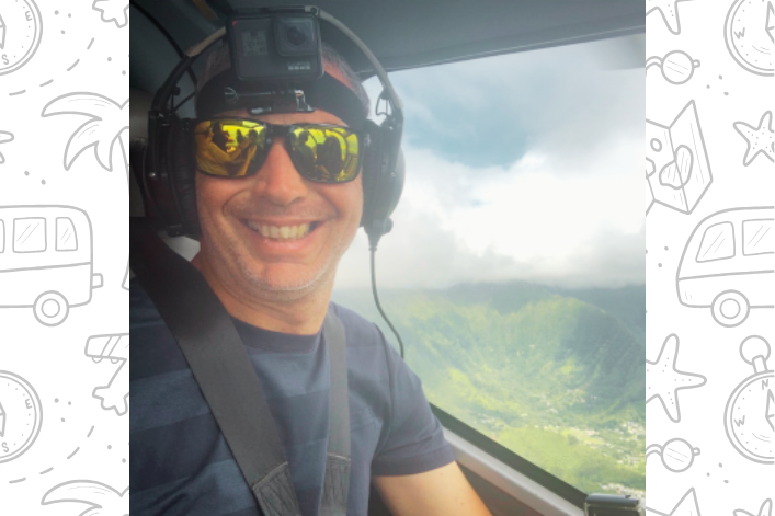 Man wearing a gopro smiling while flying in a helicopter