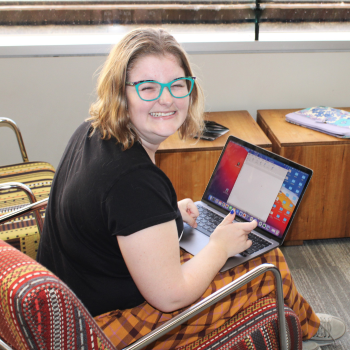 Photo of a woman smiling while typing on a laptop