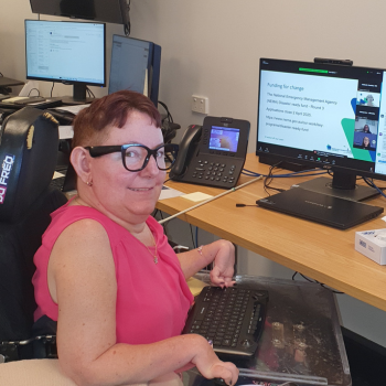Photo of a woman using audio glasses at work, with computers in the background