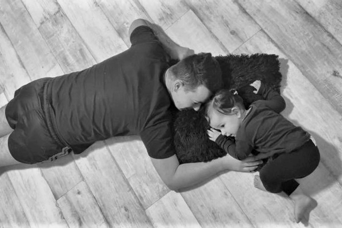 Jayden and Adelyne bw A father and his young daughter lay on the floor facing each other.