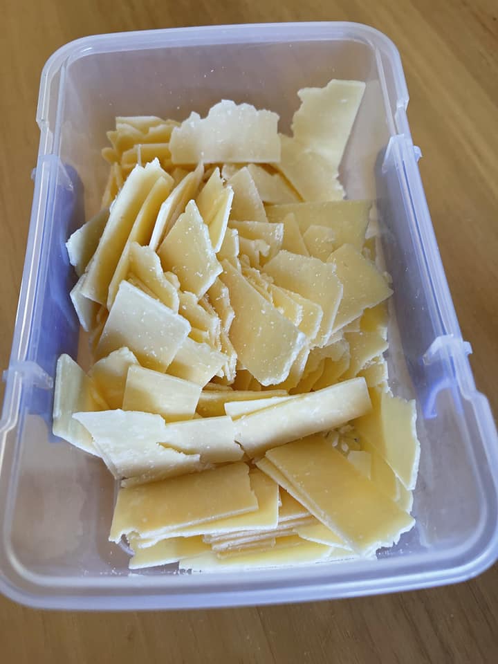 A plastic container with shavings of parmesan cheese. 