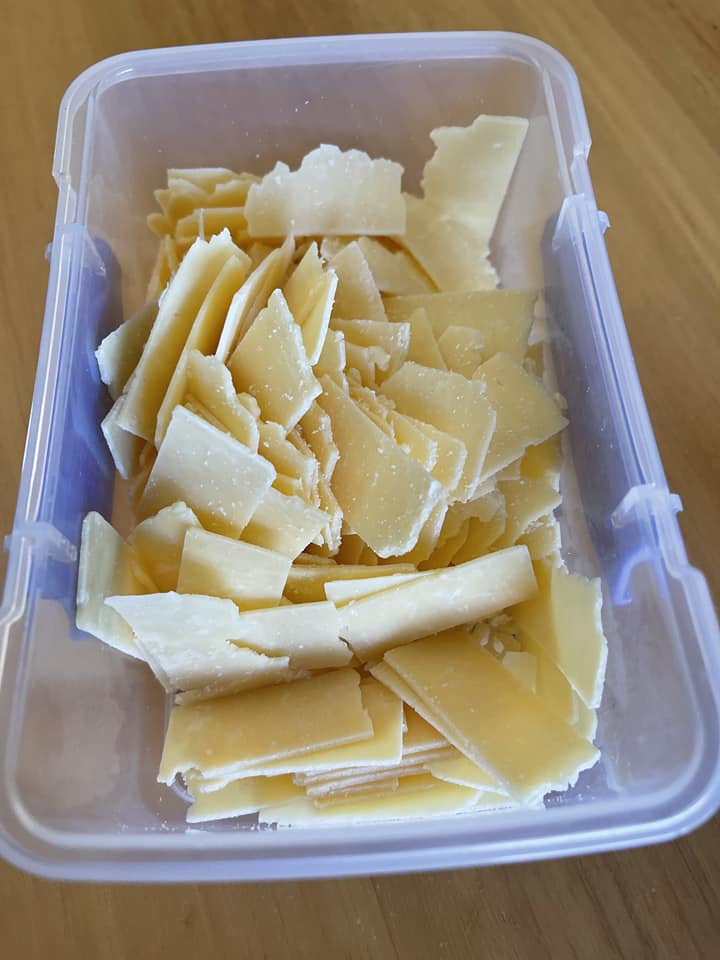 A plastic container with shavings of parmesan cheese.