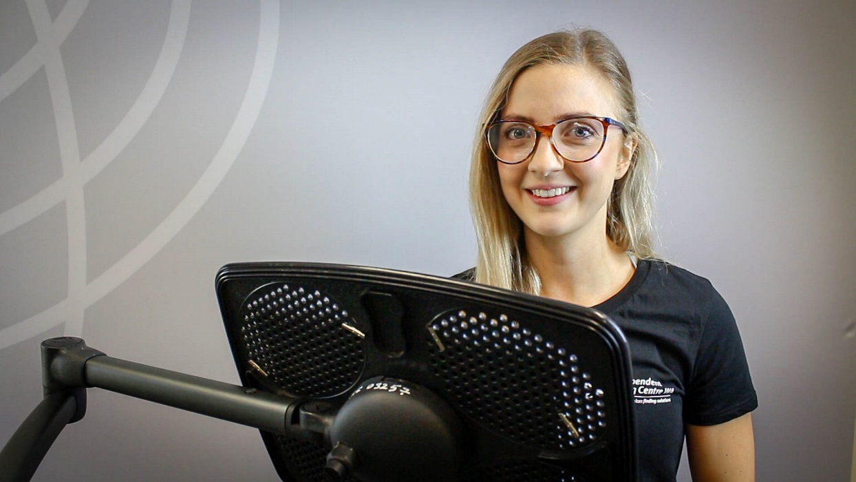 katie_ecd blonde woman wearing glasses stands in front of tablet with eye gaze equipment on it