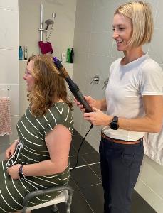 Woman is seated while a lady uses the Dyson Airwrap to style her hair