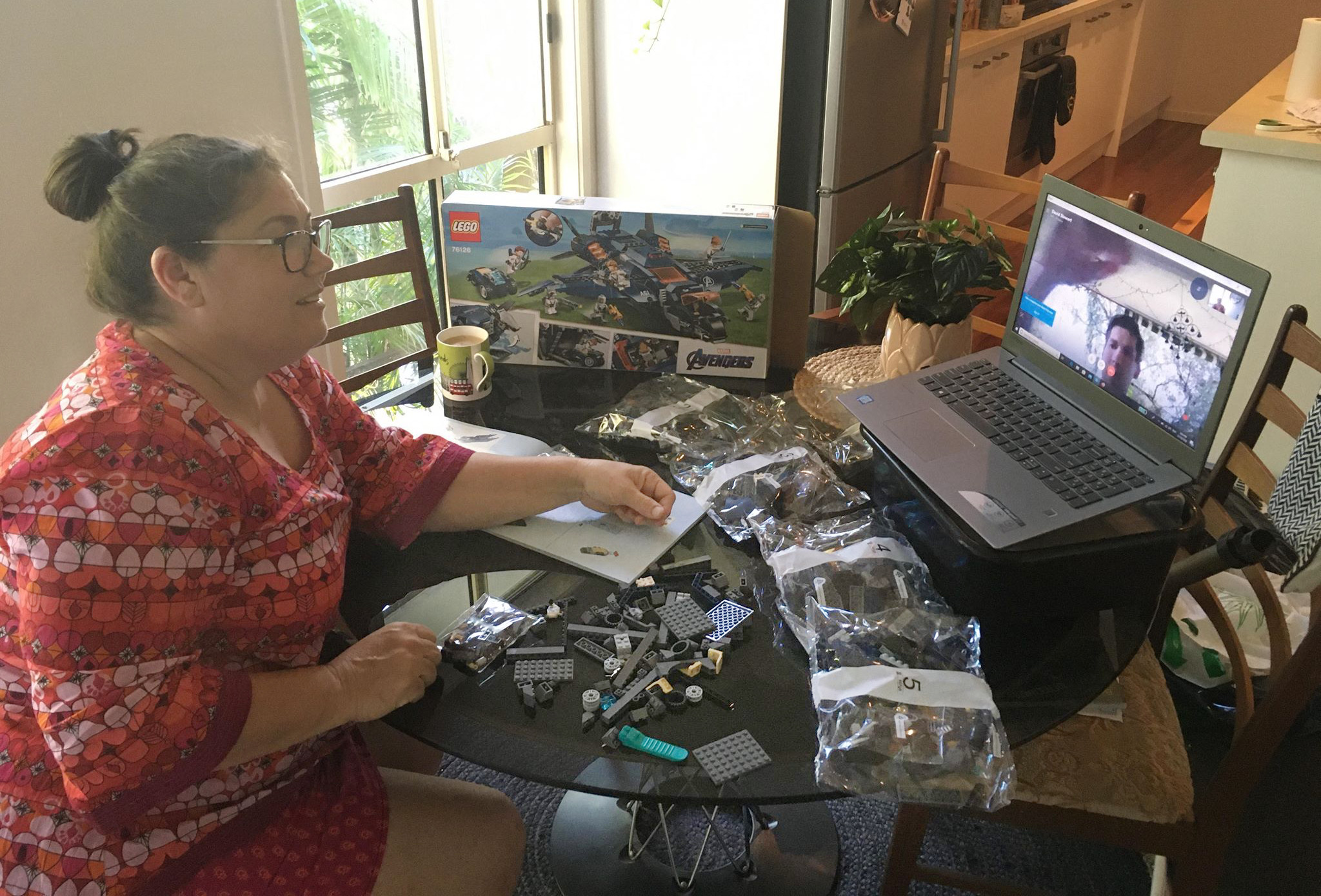 A woman builds lego whilst on a video call to a man building the same lego