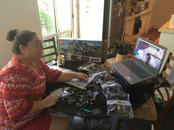 A woman builds lego whilst on a video call to a man building the same lego