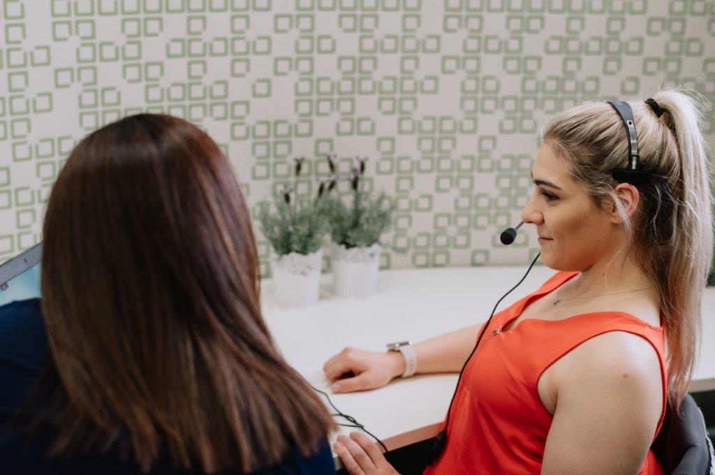 Back of female head brown hair sitting female with microphone headset sitting at desk